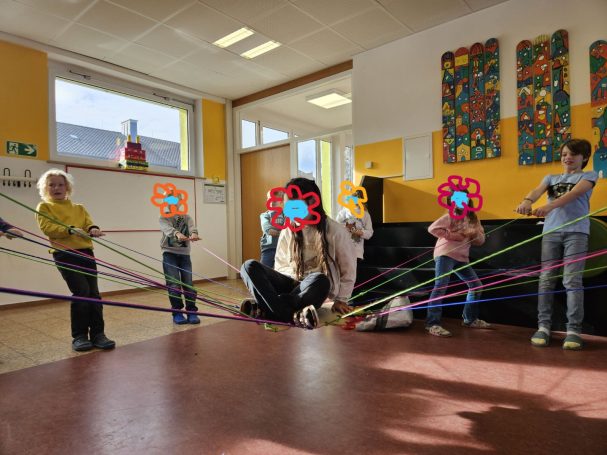 Sozialtraining Kinder halten ein Kind an einem Seilenetz hoch